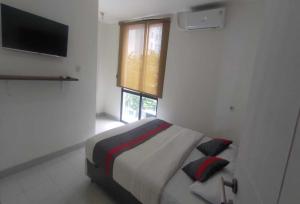 a bedroom with a bed with two pillows and a television at OYO 93958 J&B Smart Jatinegara in Jakarta