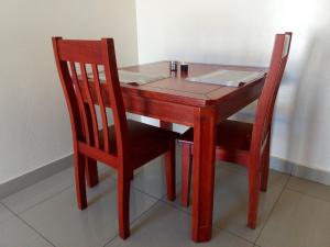 a wooden table with two chairs and a table with papers on it at Kulu Lodge Apartments in Lusaka