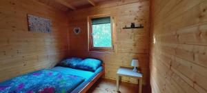 a small room with a bed in a wooden cabin at Domki Pod Jaworem in Solina
