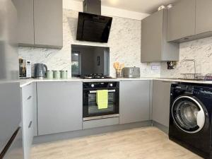 a kitchen with a stove and a washing machine at Shrewsbury Townhouse in Harlescott