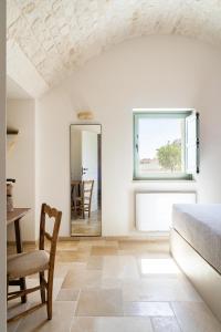 1 dormitorio con cama, mesa y espejo en Trullo Jalè - Boutique Apartments, en Ostuni