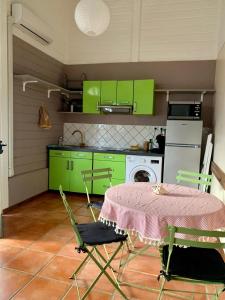 une cuisine avec des placards verts et une table avec des chaises dans l'établissement Studiodurivage2, à Ducos