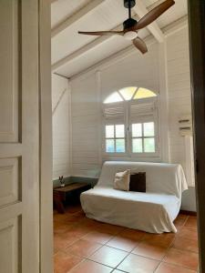 Cette chambre comprend un canapé blanc et un ventilateur de plafond. dans l'établissement Studiodurivage2, à Ducos
