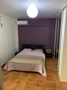 - une chambre dotée d'un lit avec un mur violet dans l'établissement Studiodurivage2, à Ducos