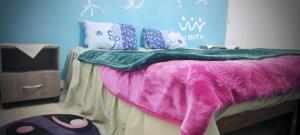 1 dormitorio con 1 cama con manta rosa y verde en Jnayna Space, en Degache