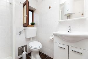 a white bathroom with a toilet and a sink at Apartment Olive with wonderful sea view - 500 m from beach in Punat +22 photos