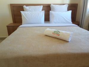 uma toalha branca sentada numa cama com um bedsenalsenalsenalsenalsenalangering em Kulu Lodge Apartments em Lusaka