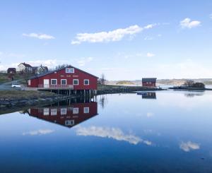 a red barn on the shore of a body of water at SAGA, unikt badehotell med 5 rom, sauna og badebrygge - Inderøy in Straumen