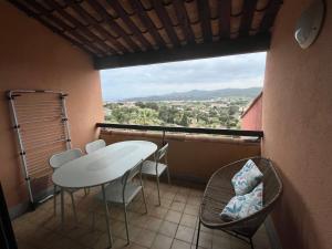 a balcony with a table and chairs and a large window at Superbe Duplex 35m2 vue mer avec piscine in Bormes-les-Mimosas