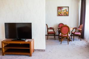 ein Wohnzimmer mit einem Flachbild-TV und Stühlen in der Unterkunft Хотел Казанлък in Kasanlak