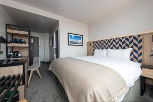a hotel room with a large bed and a desk at Sandman Signature Glasgow Hotel in Glasgow
