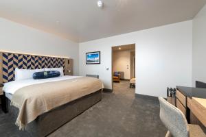 a bedroom with a large bed and a desk at Sandman Signature Glasgow Hotel in Glasgow