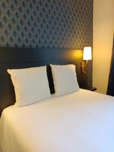1 dormitorio con 1 cama con sábanas y almohadas blancas en Logis Le Clos Deauville Saint Gatien, en Saint-Gatien-des-Bois
