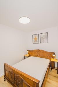 1 dormitorio con cama de madera con sábanas blancas en Dom Goscinny Bialy Dworek, en Czluchów