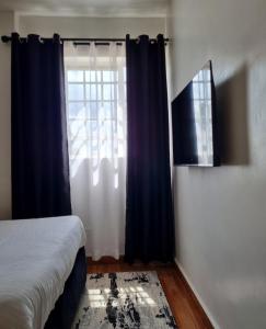 a bedroom with a bed and a window at Rossyln Home close to Village Market, UN and Two Rivers Mall in Nairobi