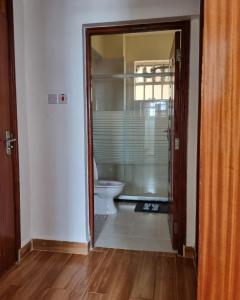 a bathroom with a toilet and a glass doorway at Rossyln Home close to Village Market, UN and Two Rivers Mall in Nairobi