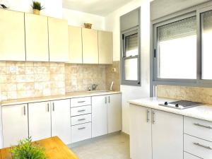 a kitchen with white cabinets and a table and a window at Two Bedrooms Duplex Apartment l Bugrashov Street l by Bookiz in Tel Aviv
