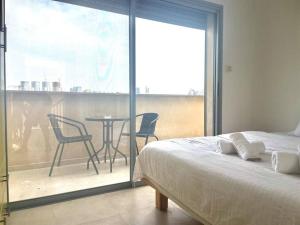a bedroom with a bed and a balcony with a table and chairs at Two Bedrooms Duplex Apartment l Bugrashov Street l by Bookiz in Tel Aviv