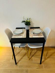 a black table with white chairs and a plant on it at Studio calais la plage in Calais