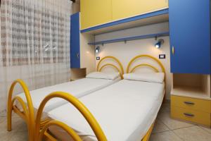 - une chambre avec 2 lits bleu et jaune dans l'établissement Villa Zanella, à Rosolina Mare
