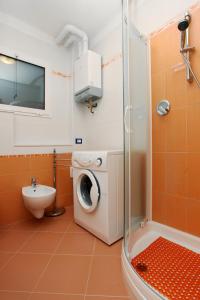 y baño con lavadora y ducha. en Villa Zanella, en Rosolina Mare