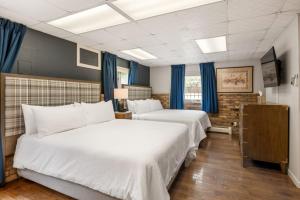 Hotel Maxwell Anderson في غلينوود سبرينغز: سريرين في غرفة فندق مع ستائر زرقاء