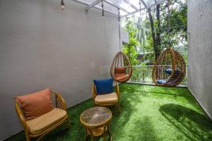 balkon z krzesłami, stołem i zieloną trawą w obiekcie Villa Cozy - Luxury Plunge Pool Villa in South Goa w mieście Benaulim