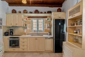 a kitchen with wooden cabinets and a black refrigerator at Cellar Villa in Xirosterni in Xirostérnion