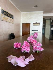 eine Gruppe rosafarbener Blumen auf einem Holztisch in der Unterkunft Хотел Казанлък in Kasanlak