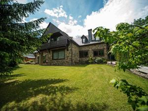 una casa con un prato verde davanti di Splendid house next to the Baqueira Beret ski resort a Vielha
