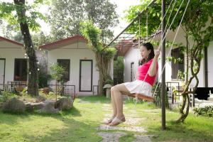 a woman sitting on a swing in front of a house at Tran Chau Garden Home in Cat Ba