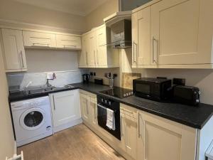 uma cozinha com armários brancos e uma máquina de lavar e secar roupa em Thurnams House, Ground Floor Apt em Carlisle