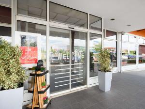 a store front with glass doors and potted plants at Ibis Budapest Citysouth in Budapest