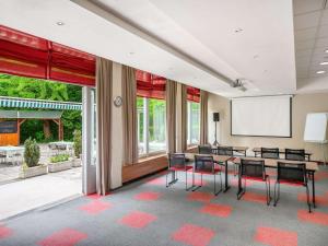 une salle de conférence avec une table, des chaises et un écran dans l'établissement Ibis Budapest Citysouth, à Budapest