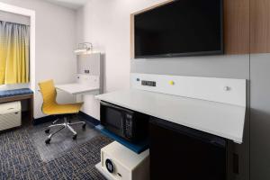 a room with a desk with a tv and a chair at Microtel Inn and Suites Dover in Dover