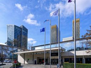 a building with blue and white flags in front of it at Novotel Luxembourg Kirchberg in Luxembourg