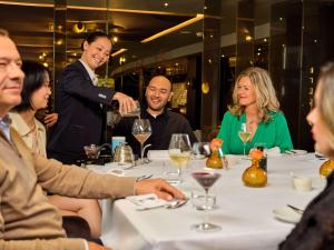 a group of people sitting around a table in a restaurant at Sofitel Legend The Grand Amsterdam in Amsterdam