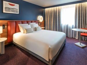 a hotel room with a large bed and a window at Mercure Caen Cote De Nacre in Caen