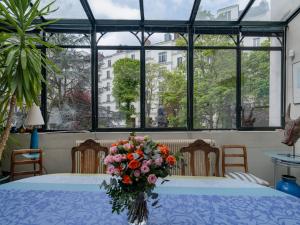un jarrón de flores sobre una mesa en una habitación con ventanas en Paris Mozart Prestige Residence, en París