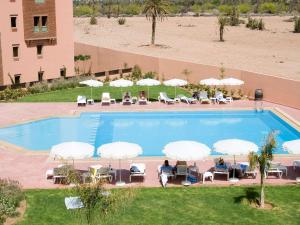 an overhead view of a swimming pool with chairs and umbrellas at Ibis Marrakech Palmeraie in Marrakech