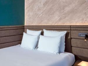 a bed with white pillows in a room at Novotel München Airport in Freising