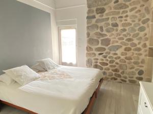 a bed in a room with a stone wall at Domaine Les Buis in Saint-Fortunat-sur-Eyrieux