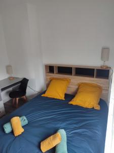 een groot bed met gele en blauwe lakens en kussens bij Chambre privée in Tarbes