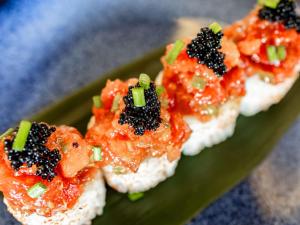 a green plate topped with three sushi with red sauce at Conrad Algarve in Quinta do Lago
