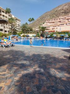 - une personne se promenant au bord de la piscine d'un complexe dans l'établissement NICE 1 BEDROOM APARTMENT LOS CRISTIANOS, à Los Cristianos
