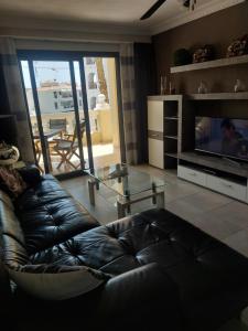 un salon avec un canapé en cuir et une table en verre dans l'établissement NICE 1 BEDROOM APARTMENT LOS CRISTIANOS, à Los Cristianos
