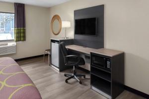 a hotel room with a desk and a television at Super 8 by Wyndham Copley Akron in Copley