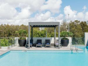 uma piscina com cadeiras e um gazebo ao lado de uma piscina em Pullman Brisbane Airport em Brisbane