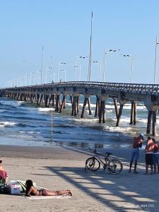 a group of people on the beach near a pier at Aconchego famíliar in Mongaguá