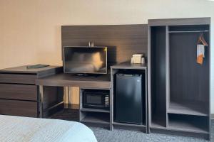 een kamer met een bureau, een televisie en een bed bij Quality Inn Spearfish in Spearfish